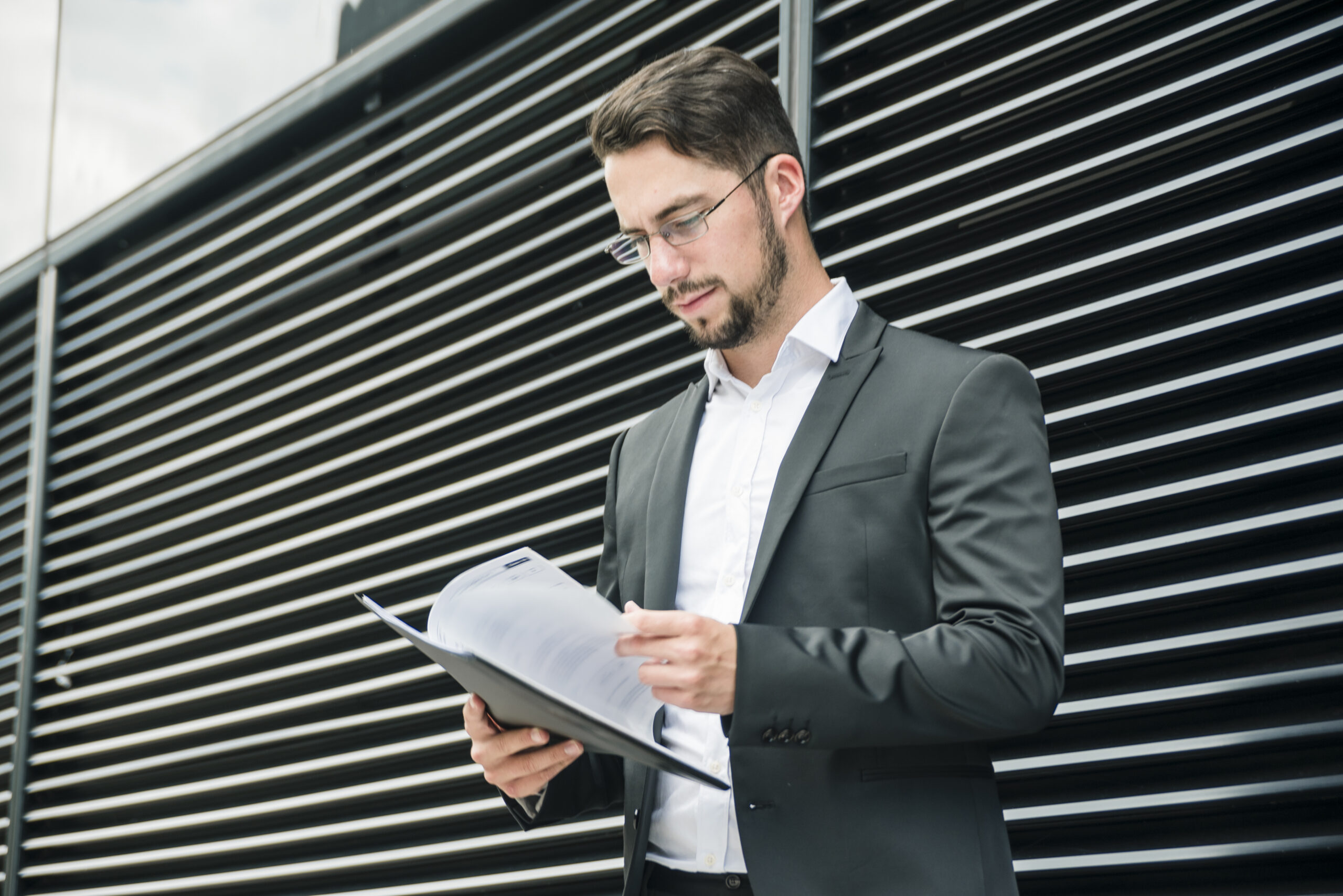 close-up-young-businessman-standing-front-wall-reading-documents